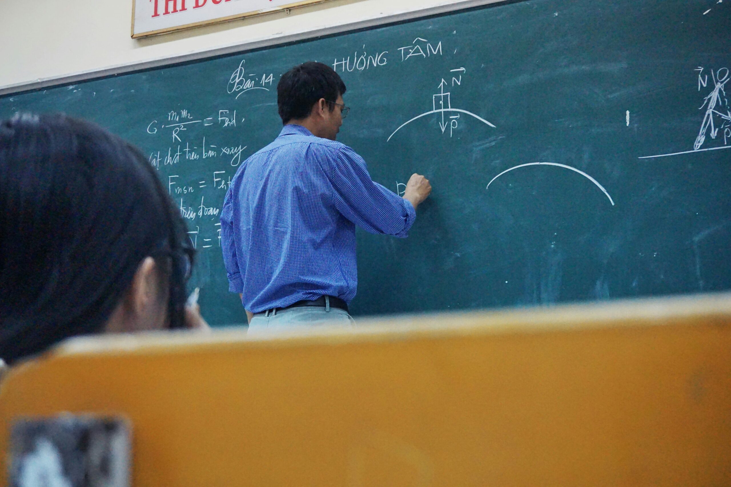 Teacher demonstrating fractions on a projector screen wearing a test calculator smartwatch