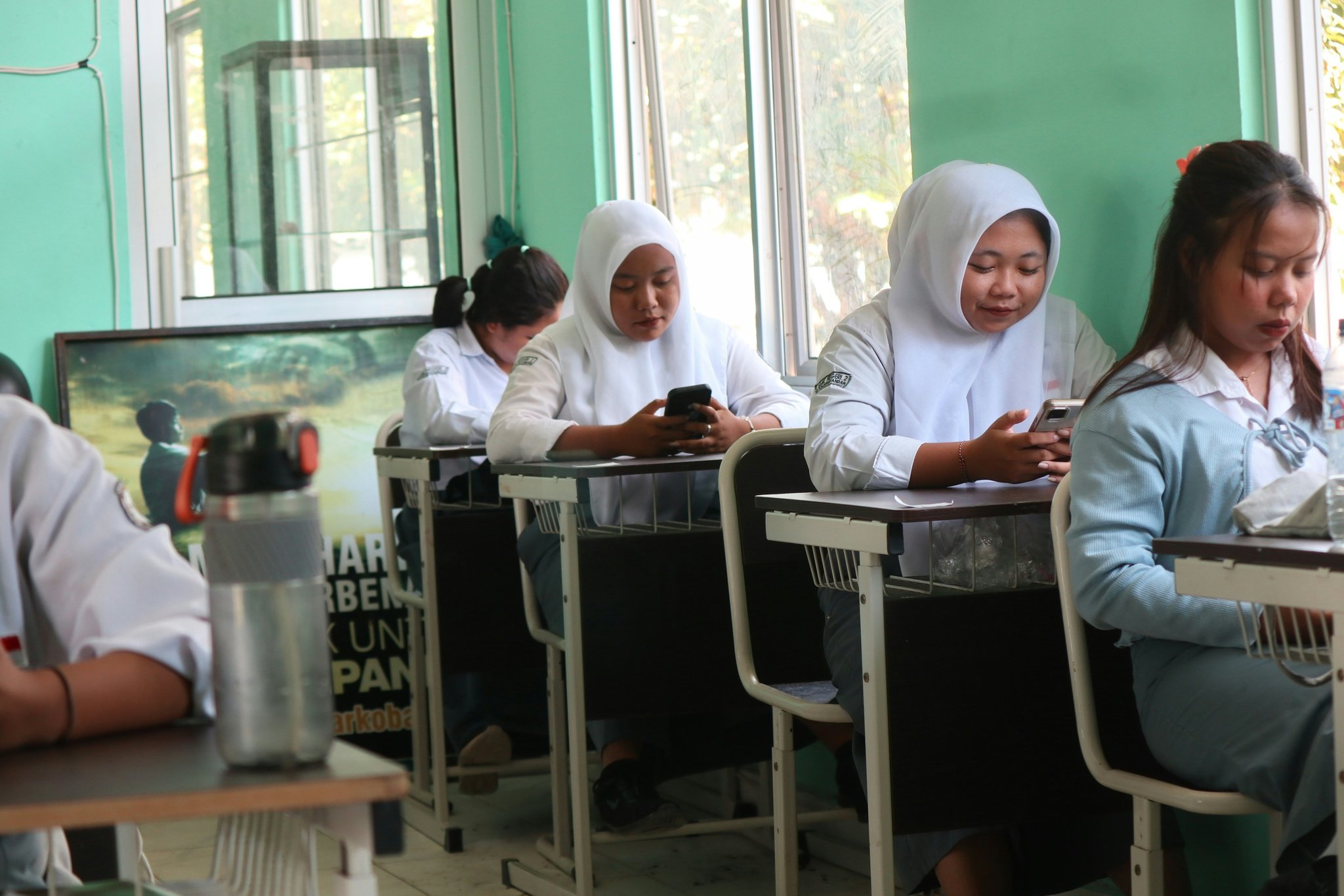 Two smiling students holding their school watches.